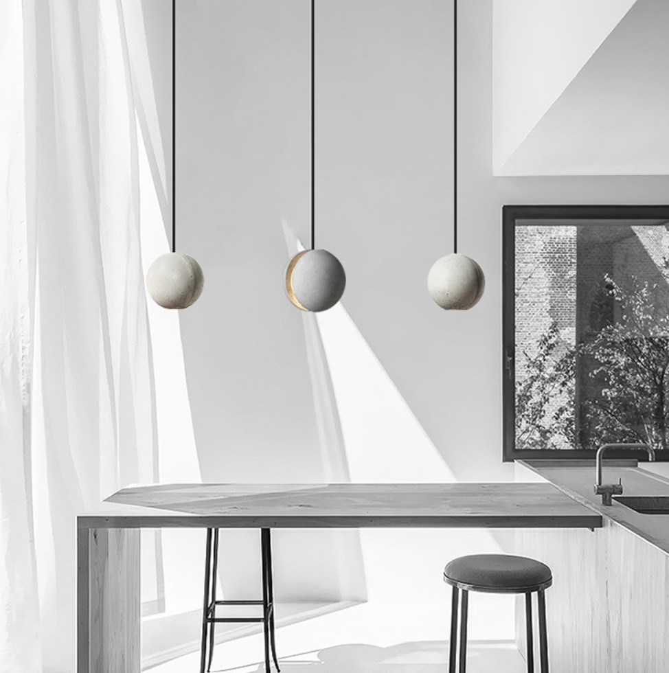 Tre betonghengte lamper over et spisebord
