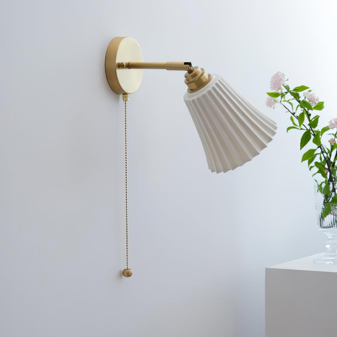 Nieoświetlona lampa ścienna w kontekście pomieszczenia z rośliną i krawędzią stołu