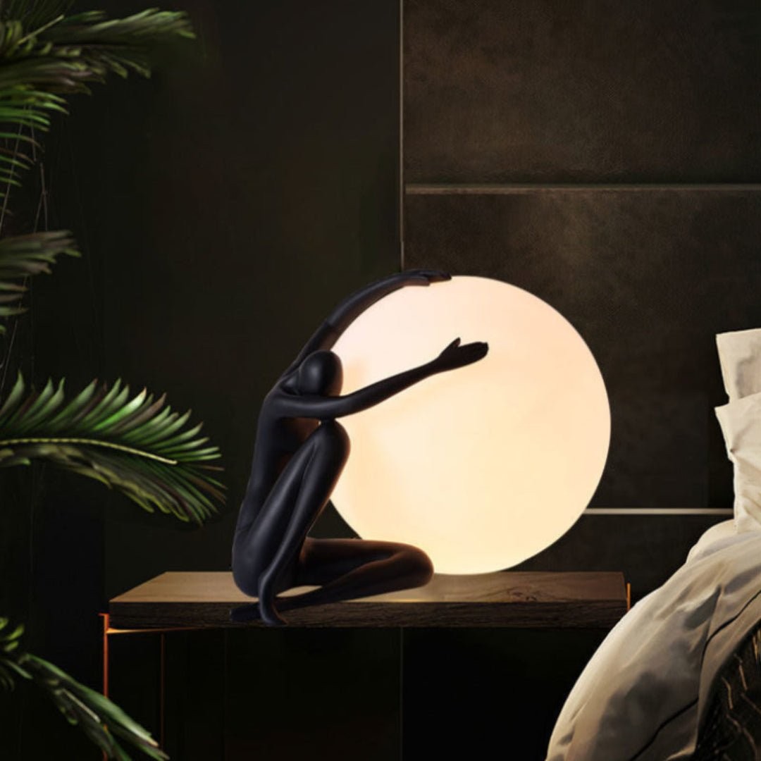 Humanoid ball som holder bordlampe M585 i en varm soveromsscene