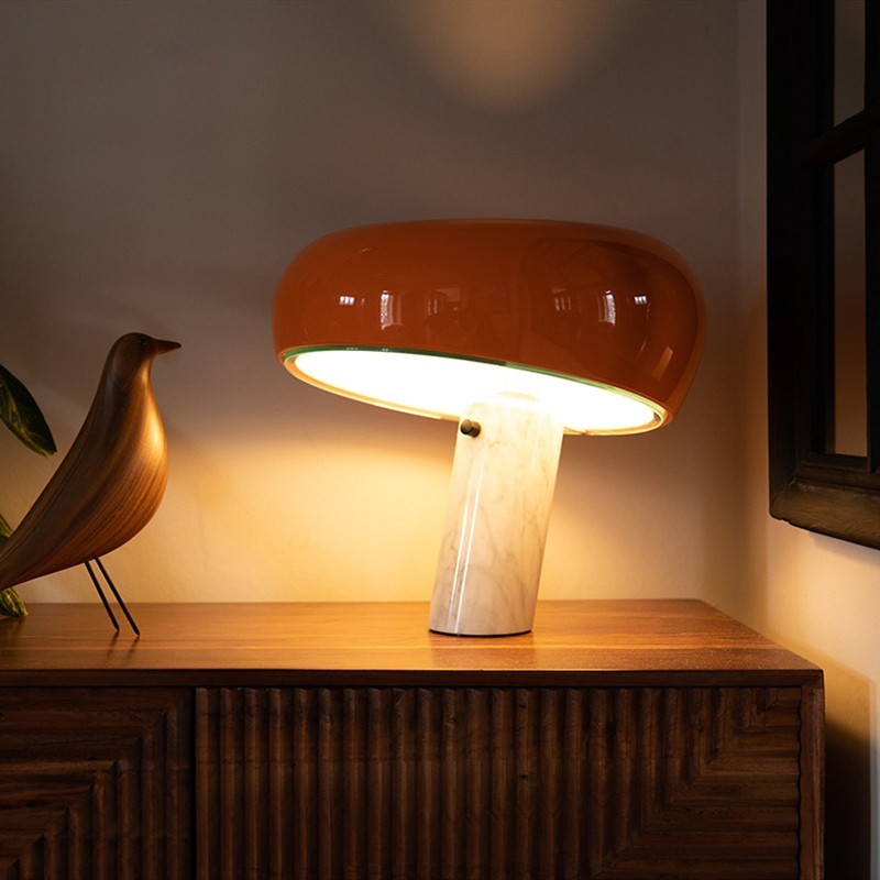 Lámpara de mesa curvada de mármol naranja iluminada sobre un armario