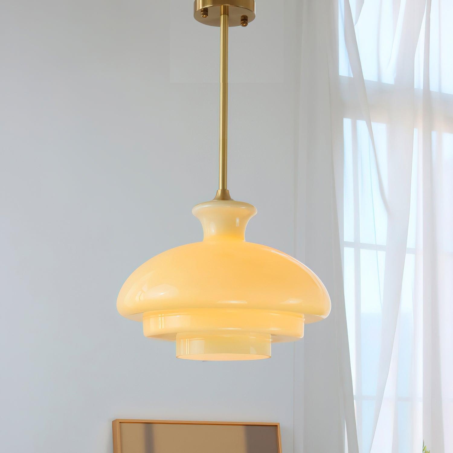 Lampa wisząca z żółtego szkła w pobliżu zasłon w jasnym wnętrzu