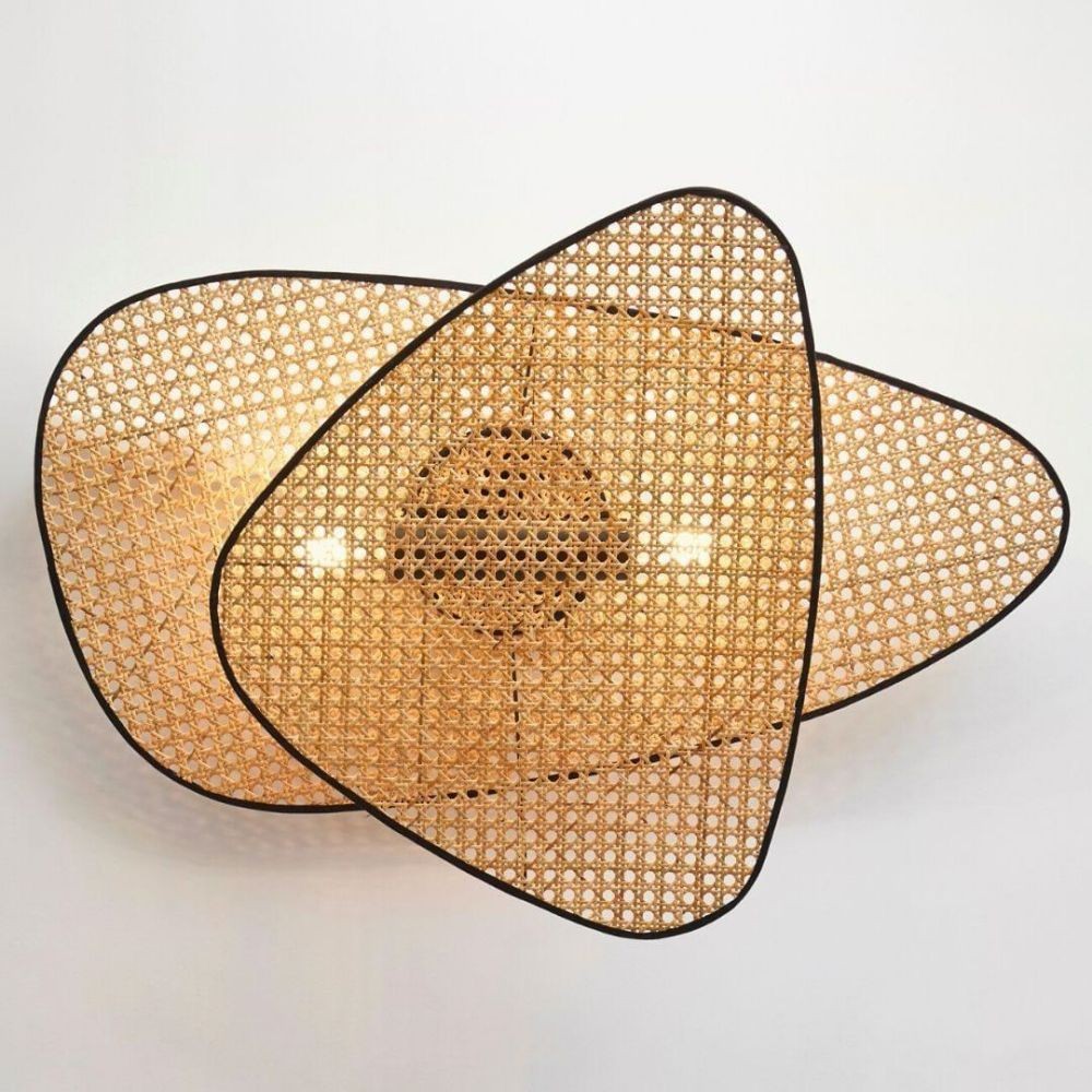 Detail einer mehrschichtigen Rattan-Wandleuchte an einer schlichten Wand