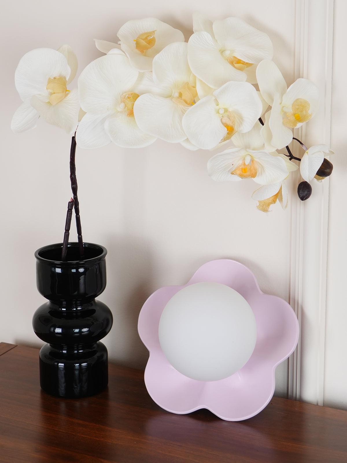 Lampa ścienna La Fleur delikatnie oświetlona obok wazonu