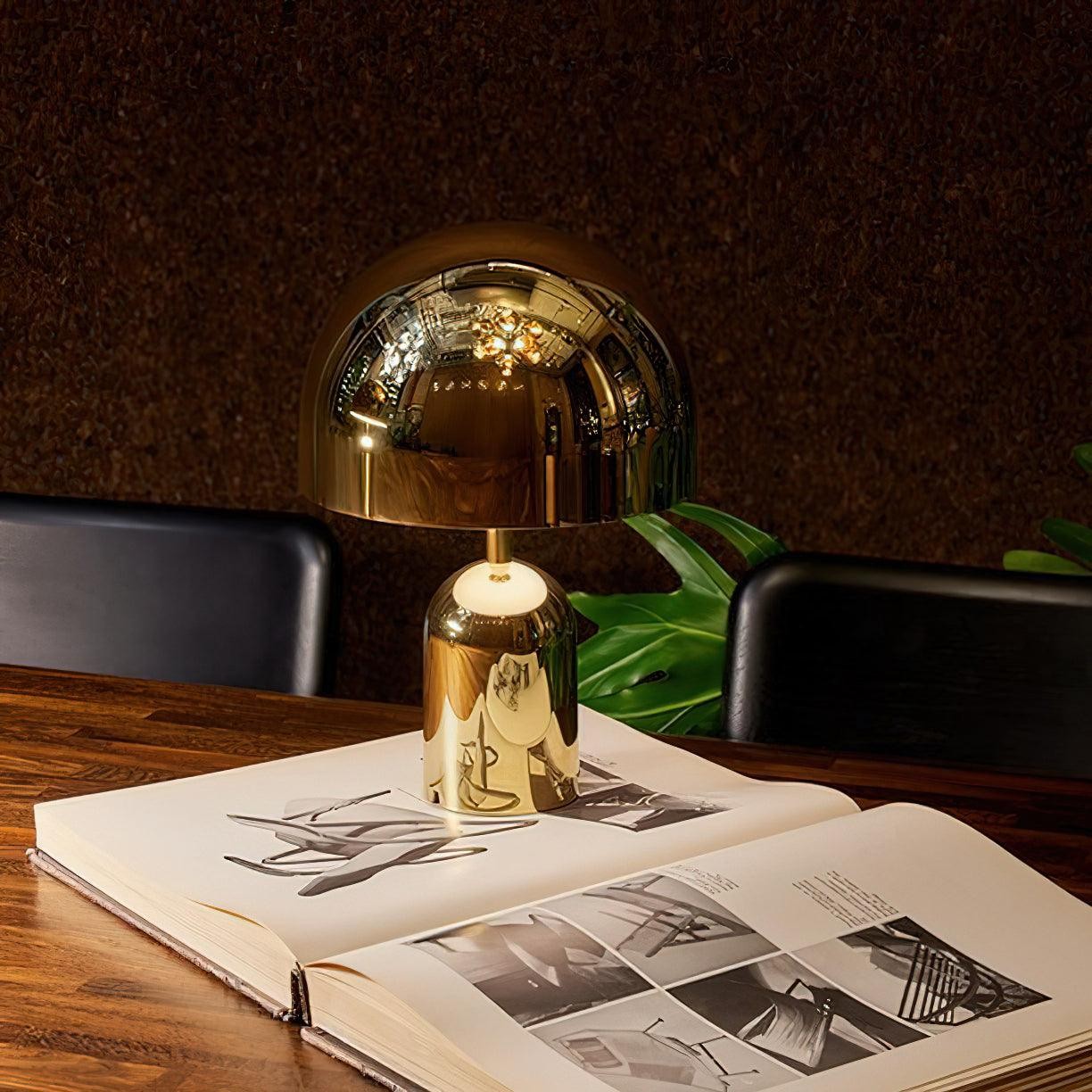 Lámpara de mesa Gold Bell sobre un libro abierto