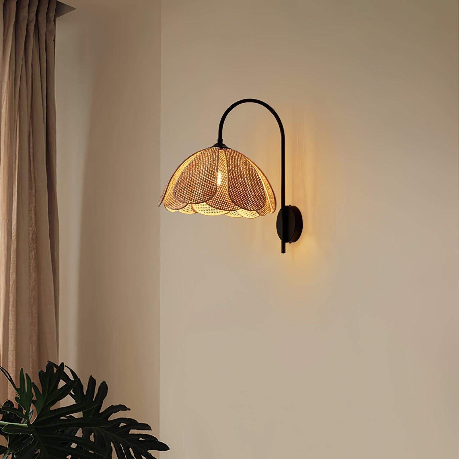 Rattanowa lampa ścienna z płatkami na jasnej ścianie w pobliżu zasłony i rośliny