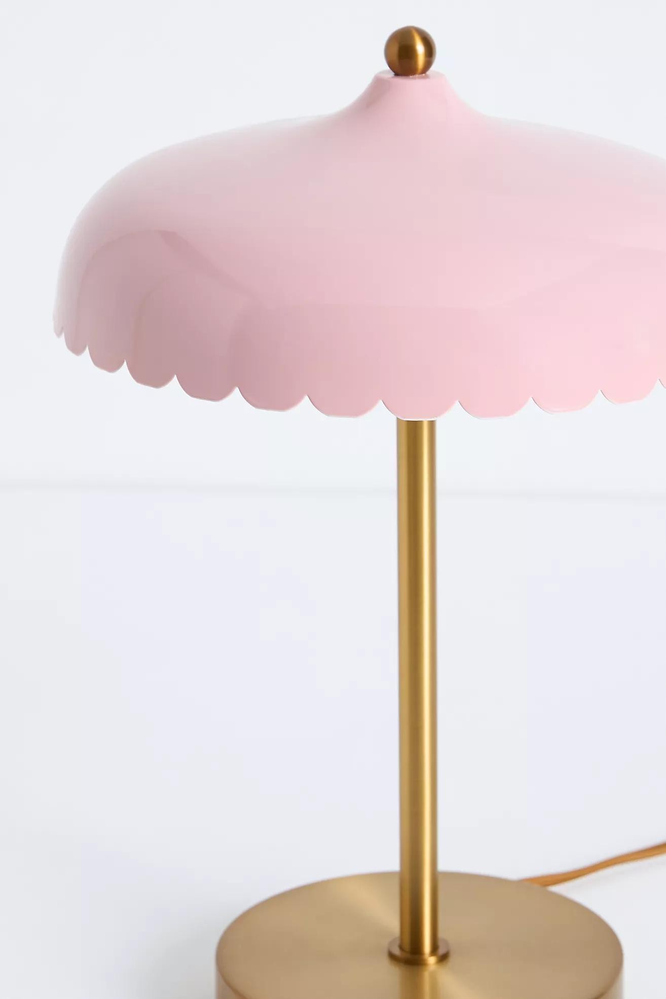 Närbild på rosa Rayla-lampa med vågig skärm och guldfärgad stjälk