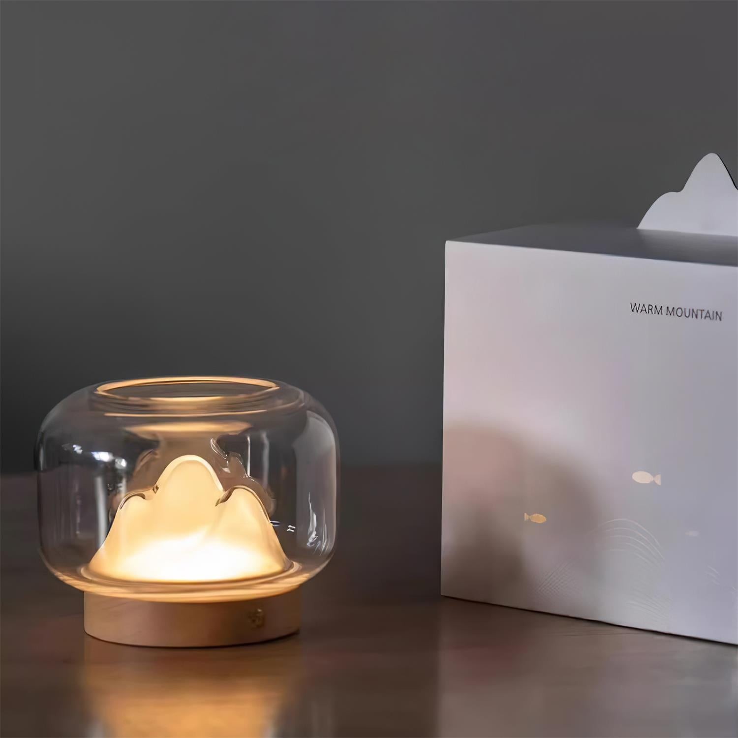 Lampa stołowa Warm Mountain świecąca obok opakowania