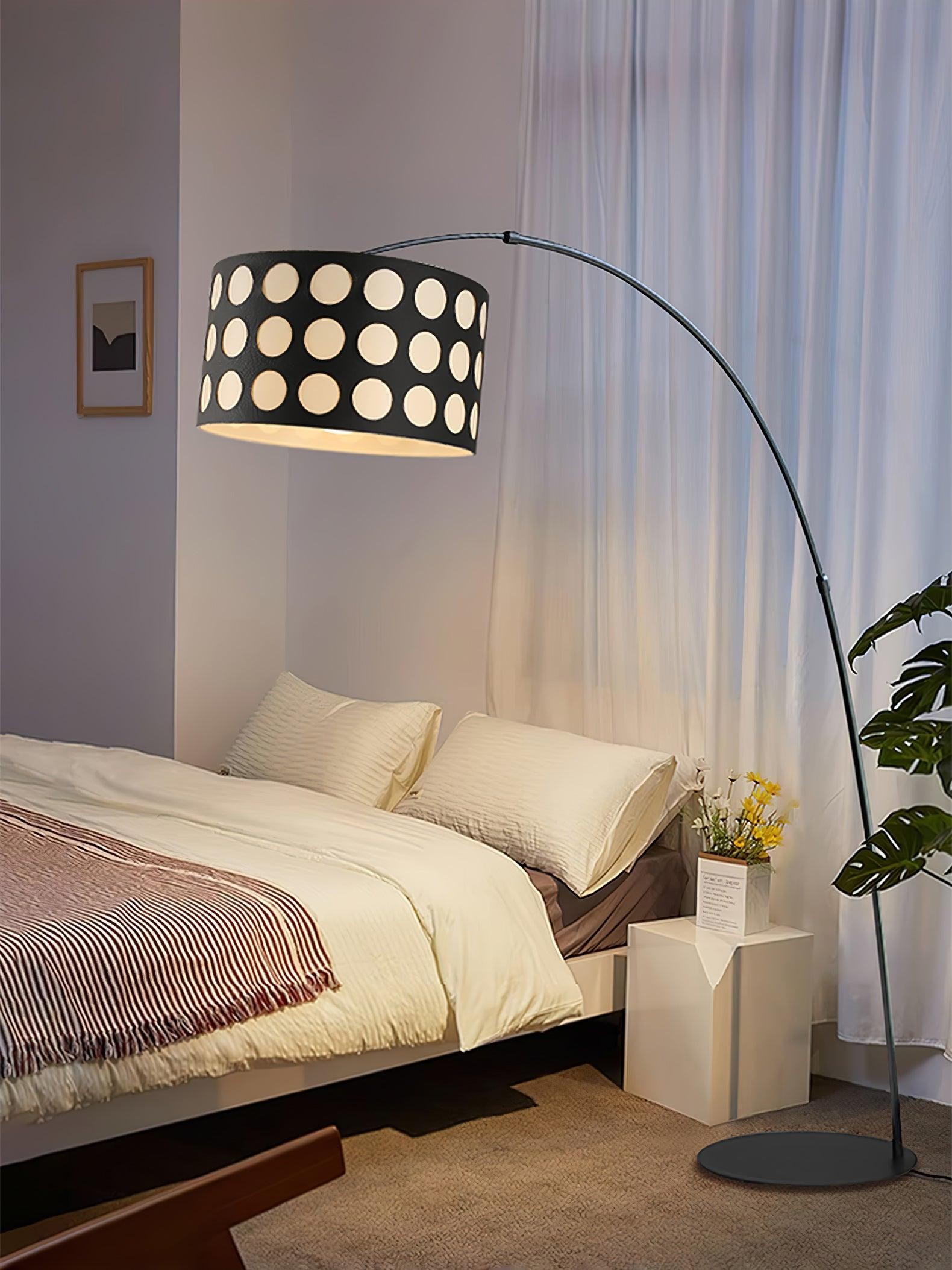 Lámpara de pie de tela con forma de arco junto a la cama.