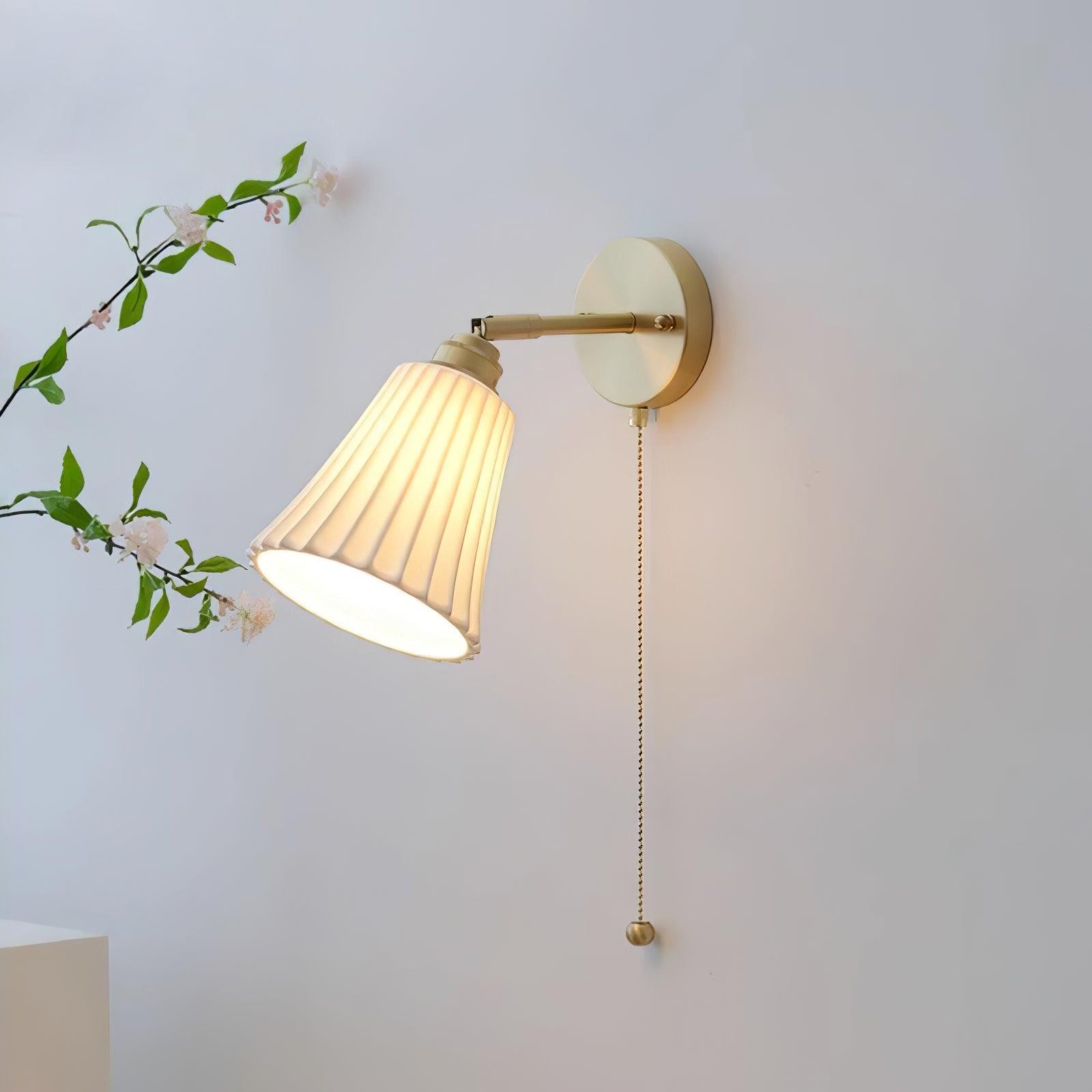 Oświetlana lampa ścienna z widocznym kloszem na ramieniu i łańcuszkiem