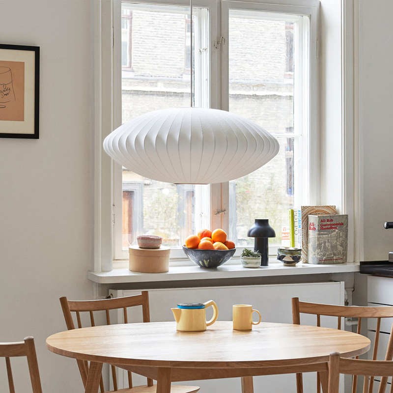 Lámpara colgante con forma de platillo sobre una mesa de comedor en un entorno de cocina.