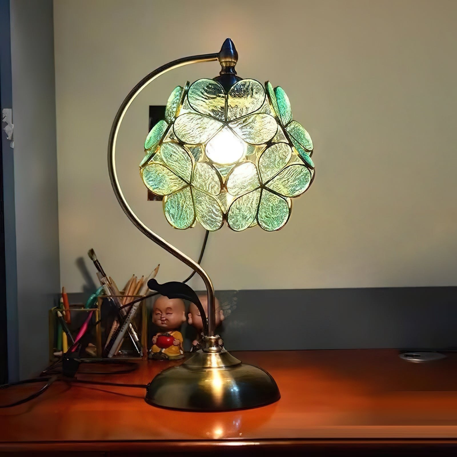 Bordlampe i petalglass tent på et skrivebord i et rom