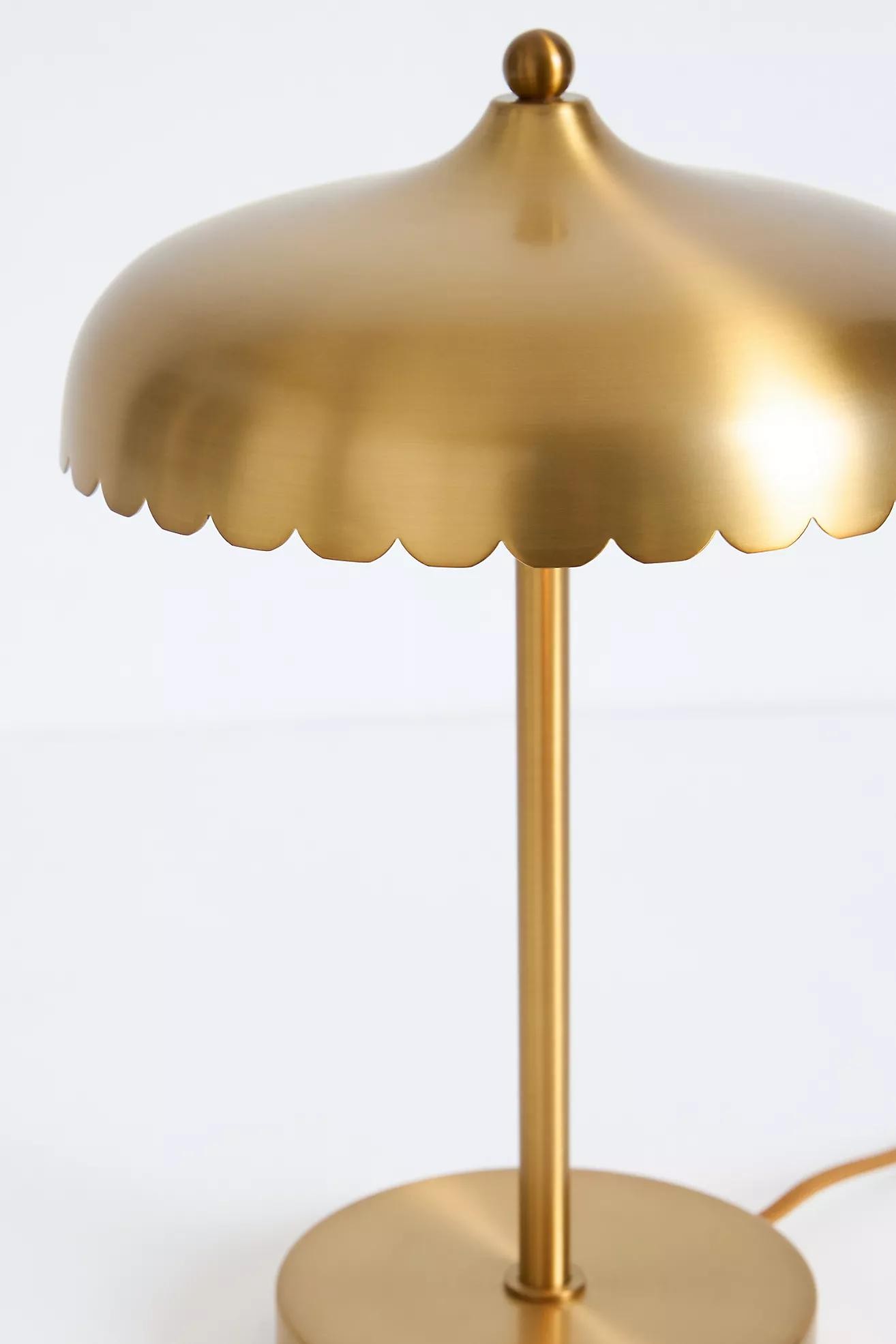 Närbild på guldfärgad Rayla-lampa som visar en vågig skärm och metallisk finish