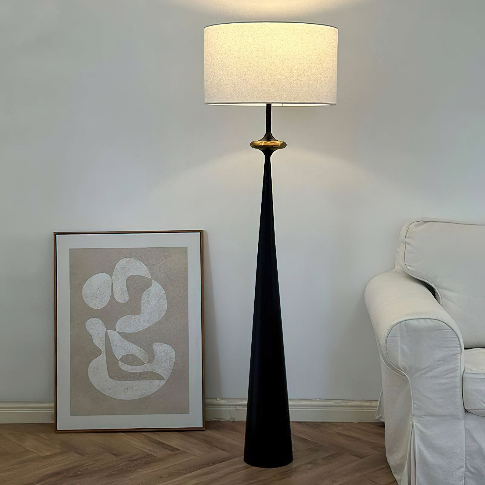 Lámpara de pie Putney T426 iluminada en una habitación con cuadros enmarcados.