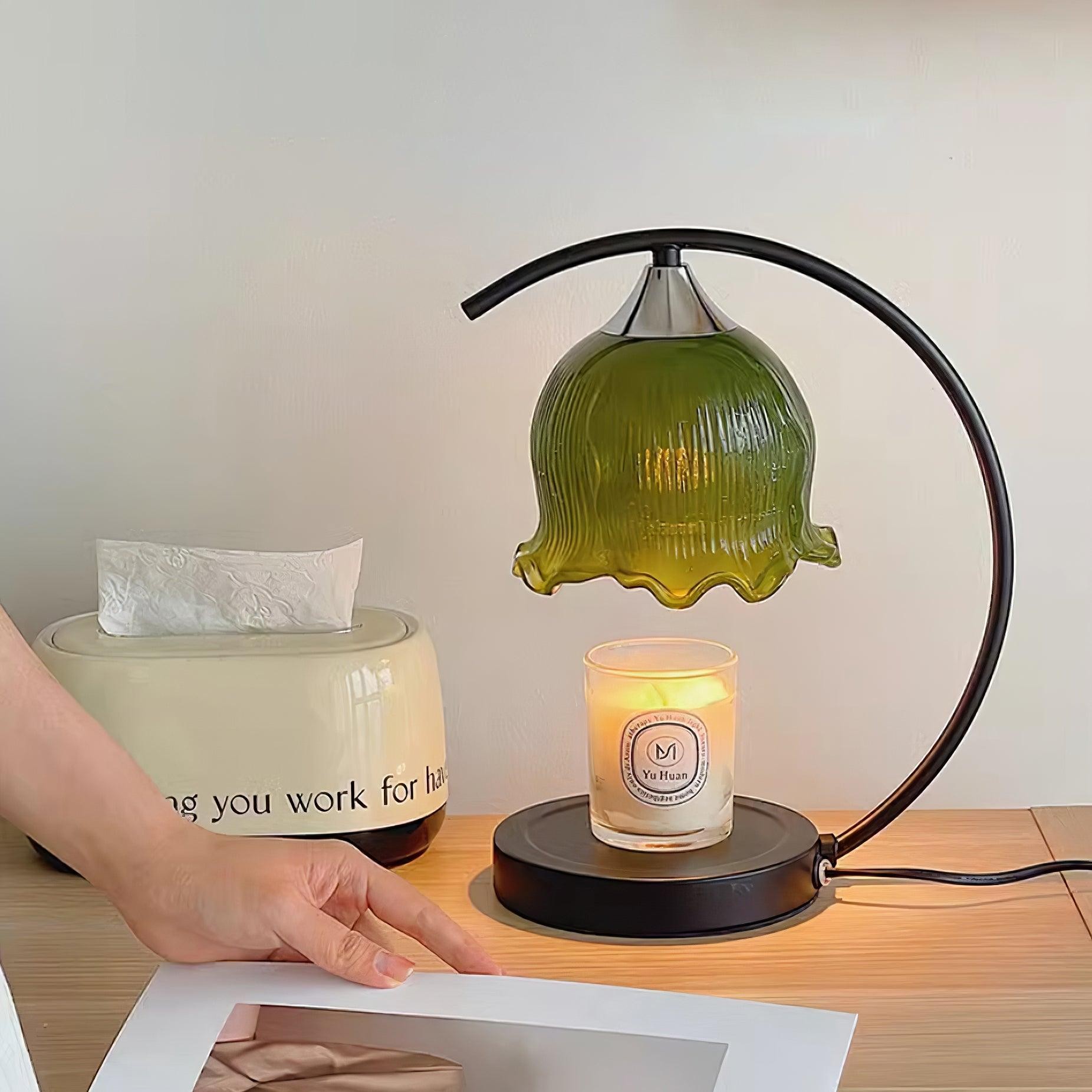 Czarno-zielona lampa podgrzewająca świece na biurku z zapaloną świecą