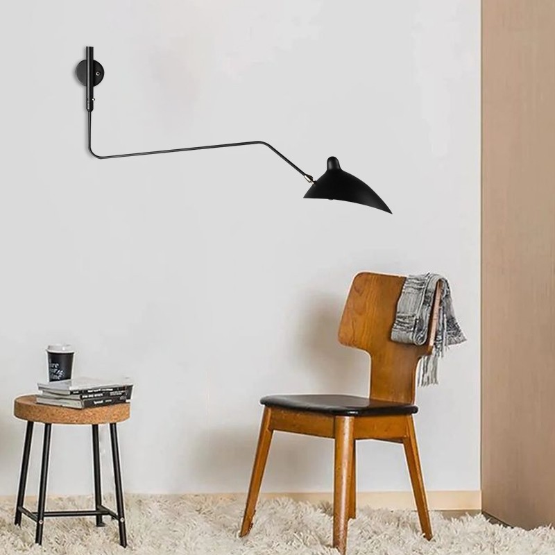 Svart andenebb-vegglampe installert i nærheten av en stol og et sidebord