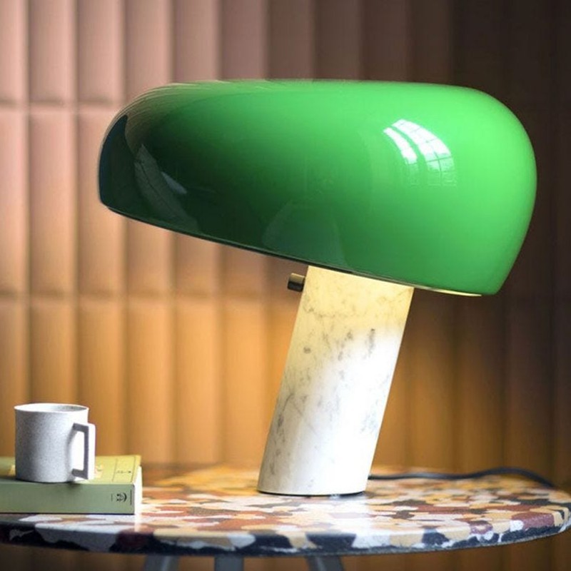 Lámpara de mesa curva de mármol verde sobre una mesa en un interior cálido.