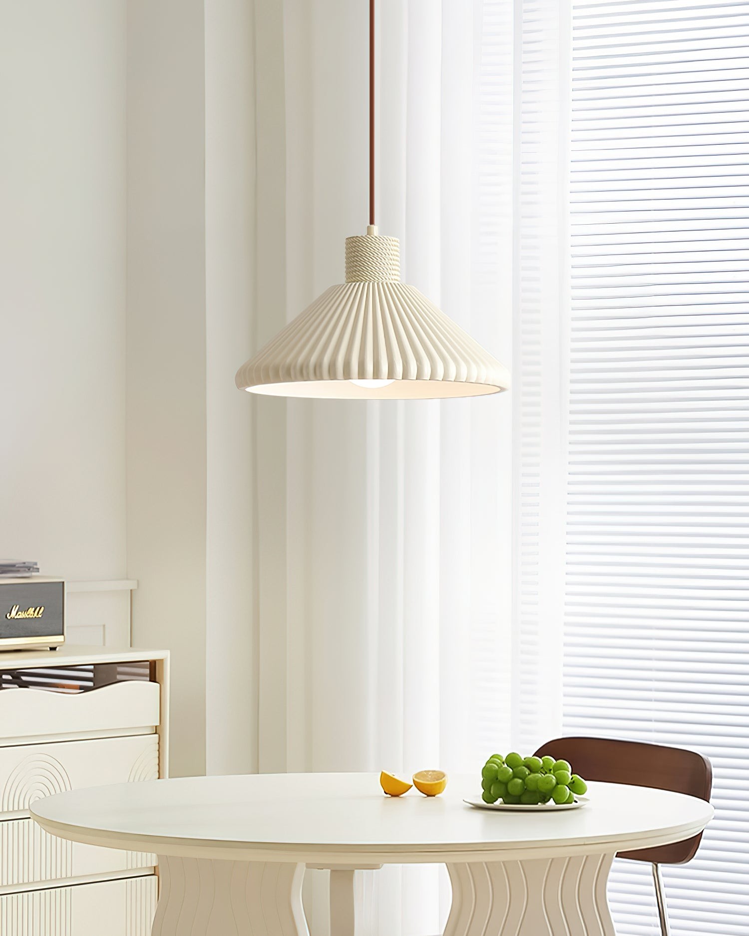 Kremowa lampa wisząca w pobliżu jasnego okna jadalni