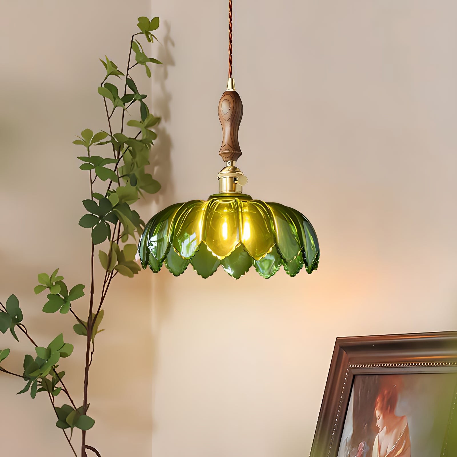 Grønn kronbladslampe som lyser i et rom med plante og innrammet kunst