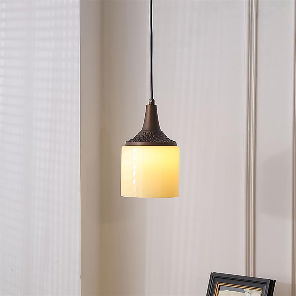 Cylindryczna lampa wisząca świecąca na tle miękkich zasłon