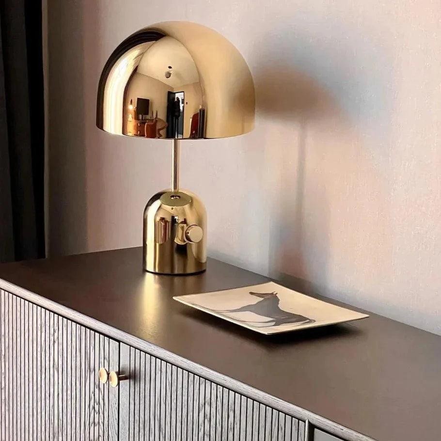 Lámpara de mesa Gold Bell sobre un mueble