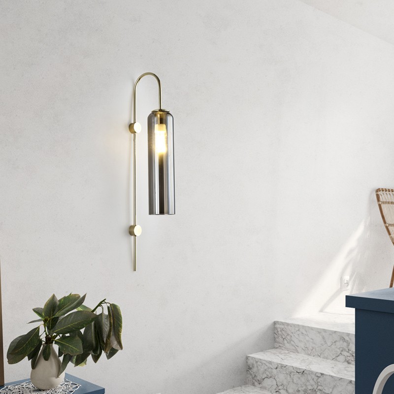 Scène minimaliste dans une pièce avec une applique murale cylindrique allumée près de l'escalier