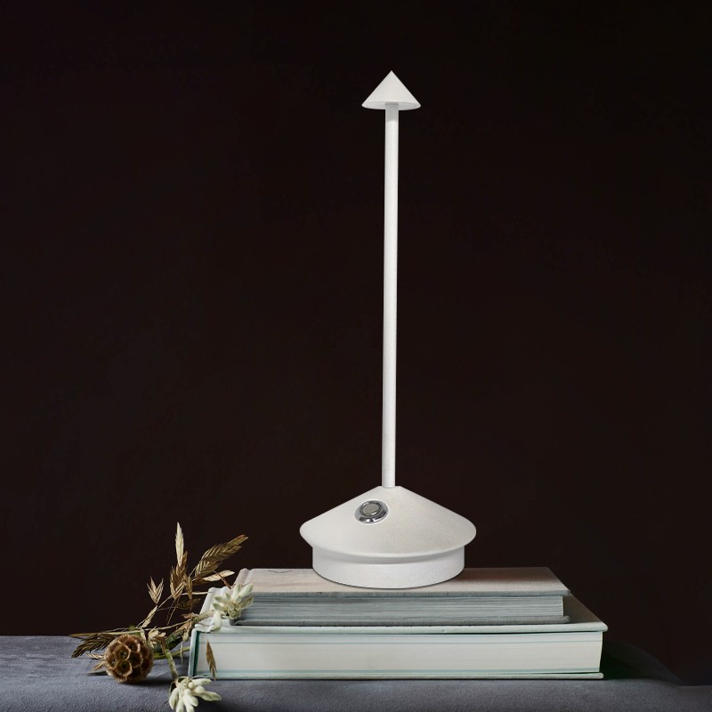 White Pina lamp on stacked books against a dark wall