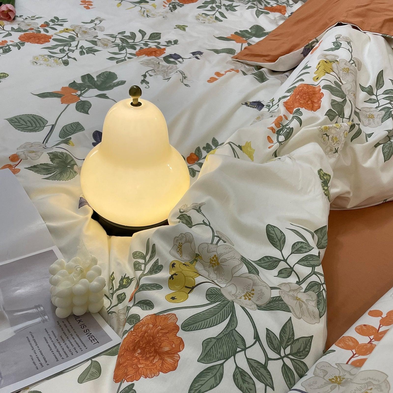Zapalona gruszkowa lampa na kwiecistej pościeli