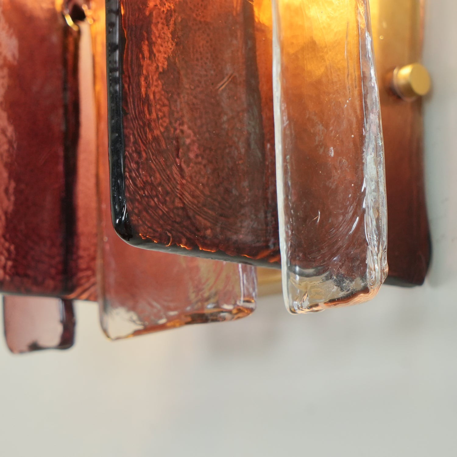 Primer plano de las tiras de cristal color coñac de la lámpara de pared Blason.