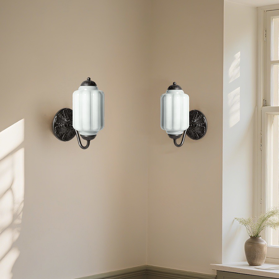To vintage vegglamper formet som lysestaker i glass installert i et hjørne av et rom