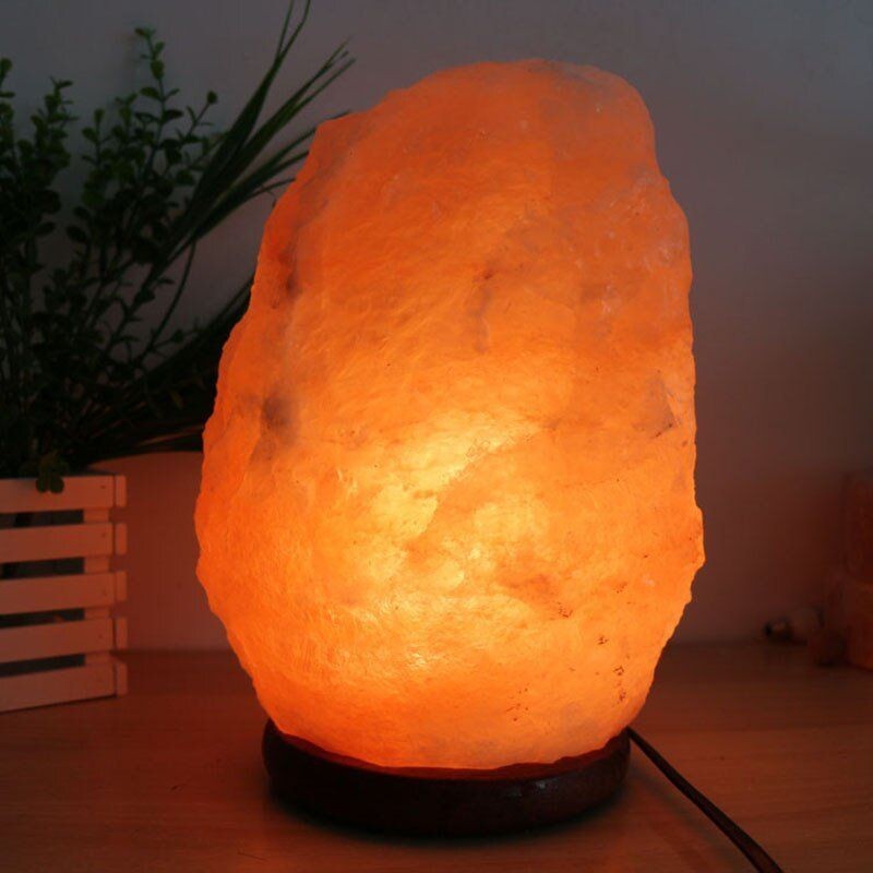 Lámpara de mesa ancha de sal del Himalaya brillando sobre una mesa.