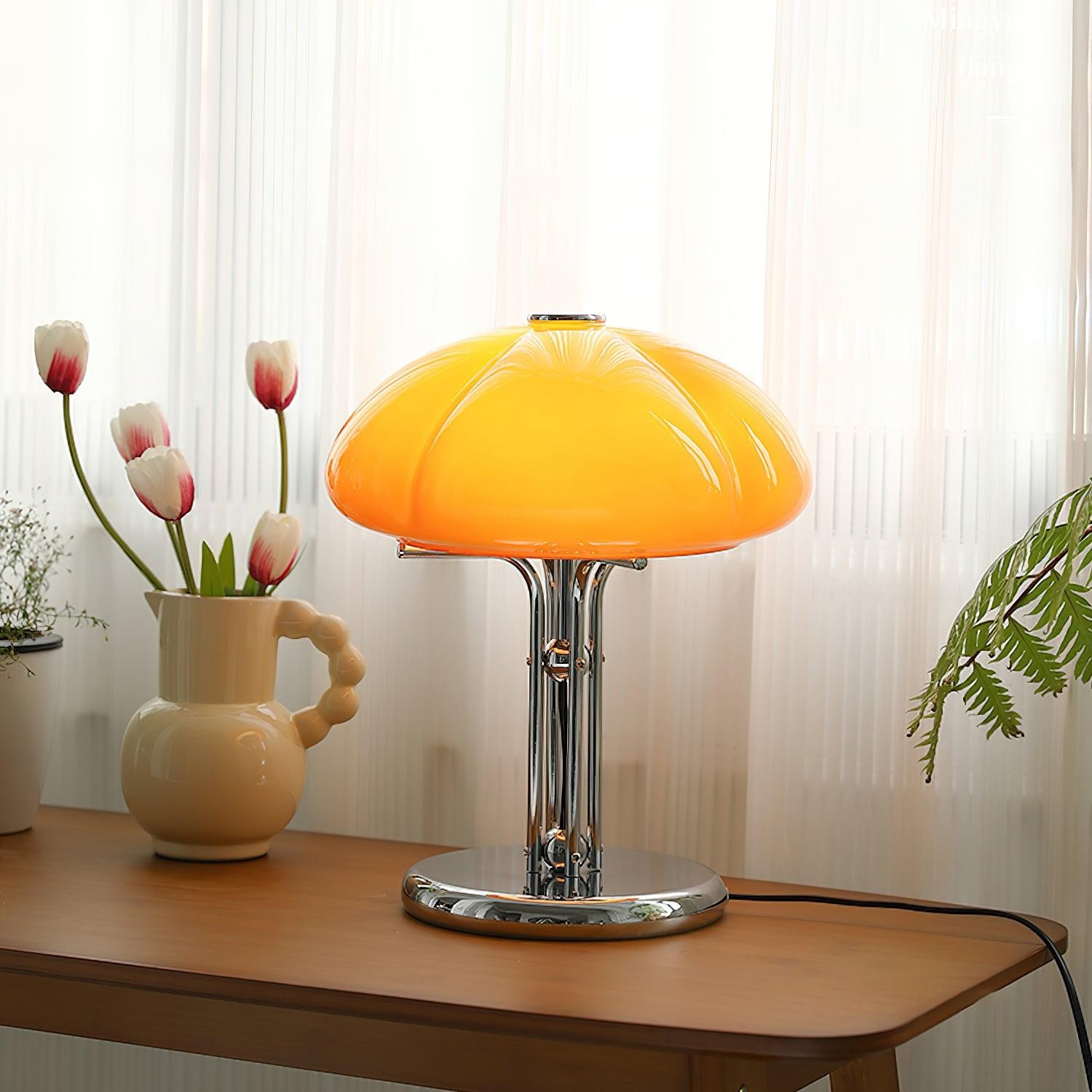 Pomarańczowa lampa na drewnianym biurku z zasłonami i kwiatami