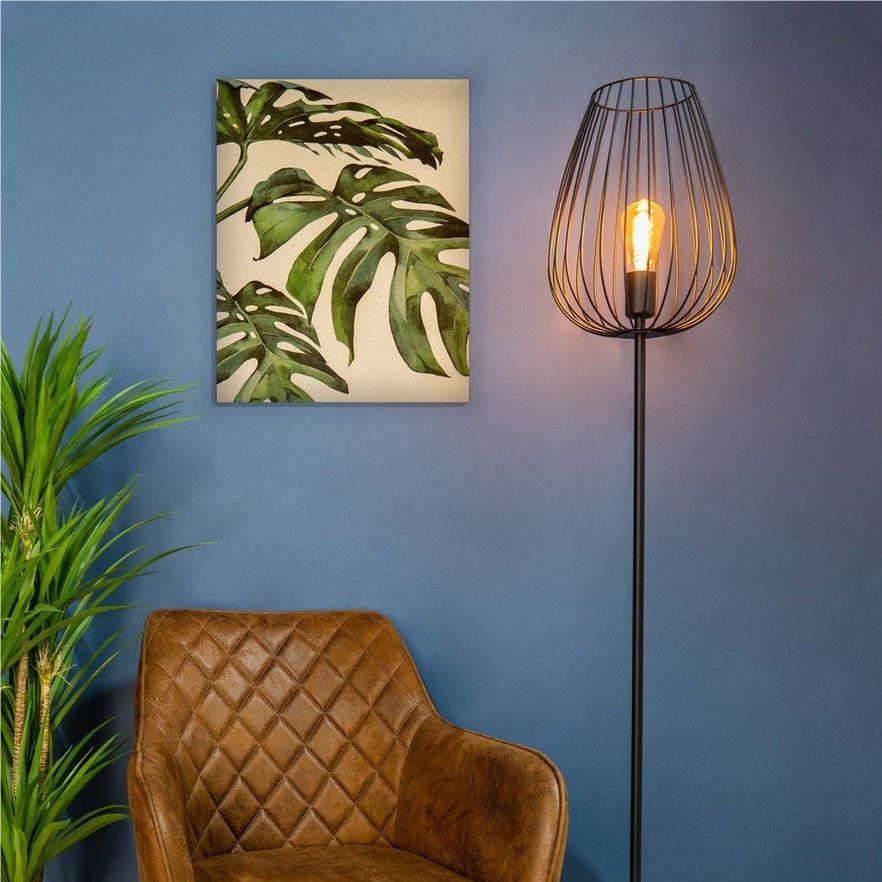 Lámpara de pie S69 encendida junto a una silla y plantas.