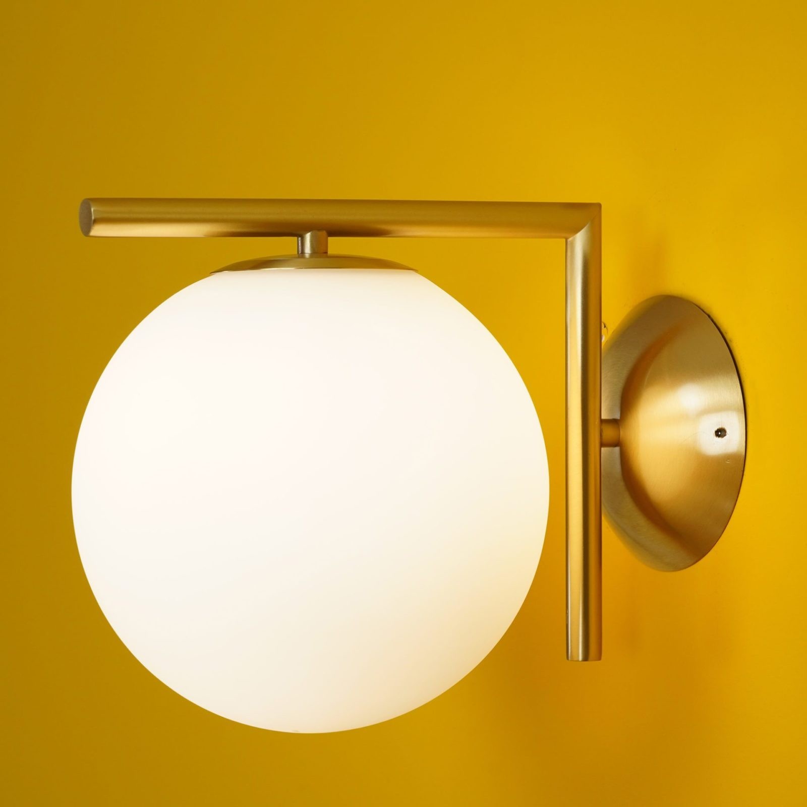 Nærbilde av messing globeformet vegglampe med brakettdetaljer