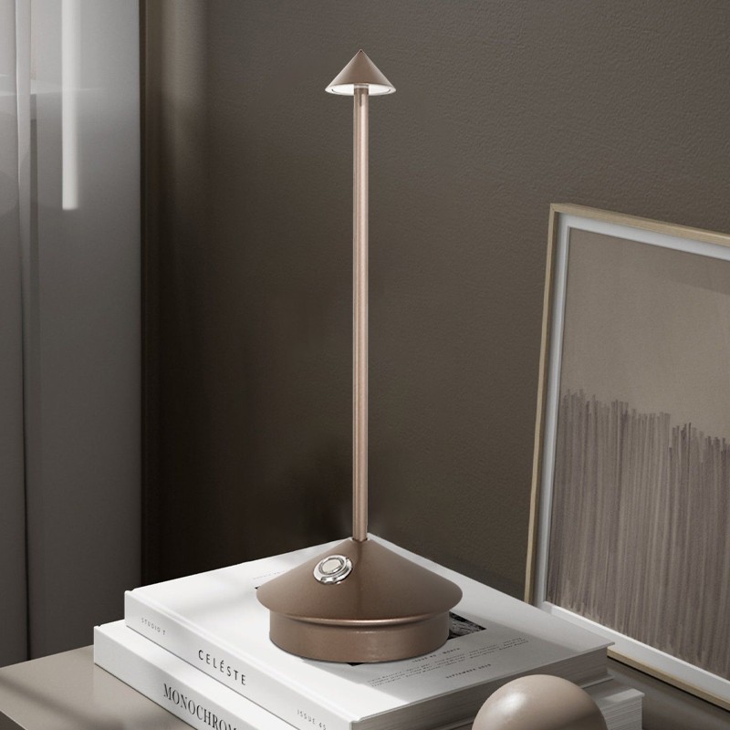 Pina lamp on stacked books beside framed art
