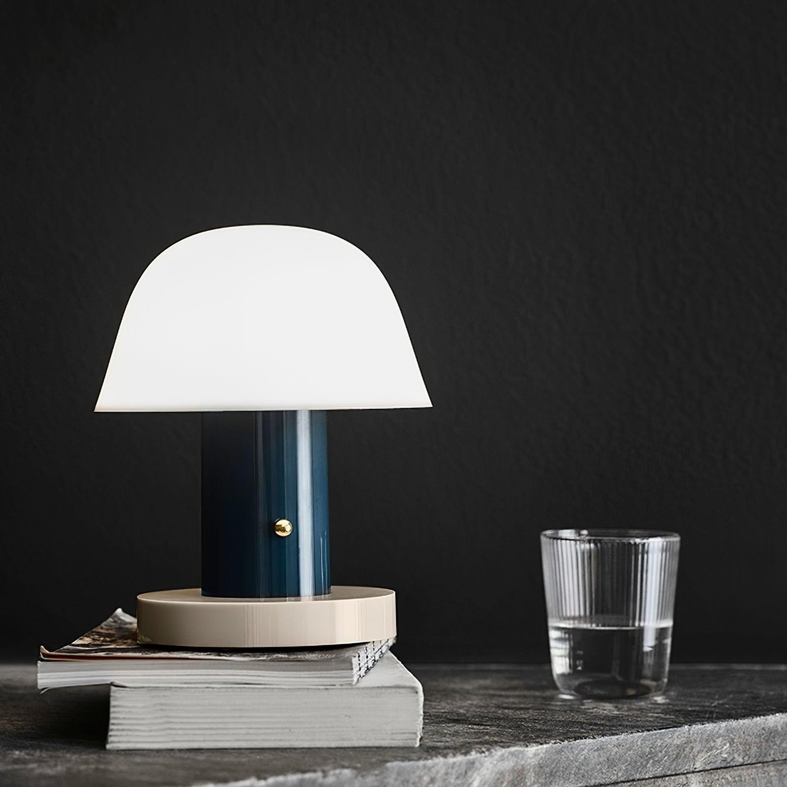 Sopplignende trådløs lampe på bøker mot en mørk bakgrunn