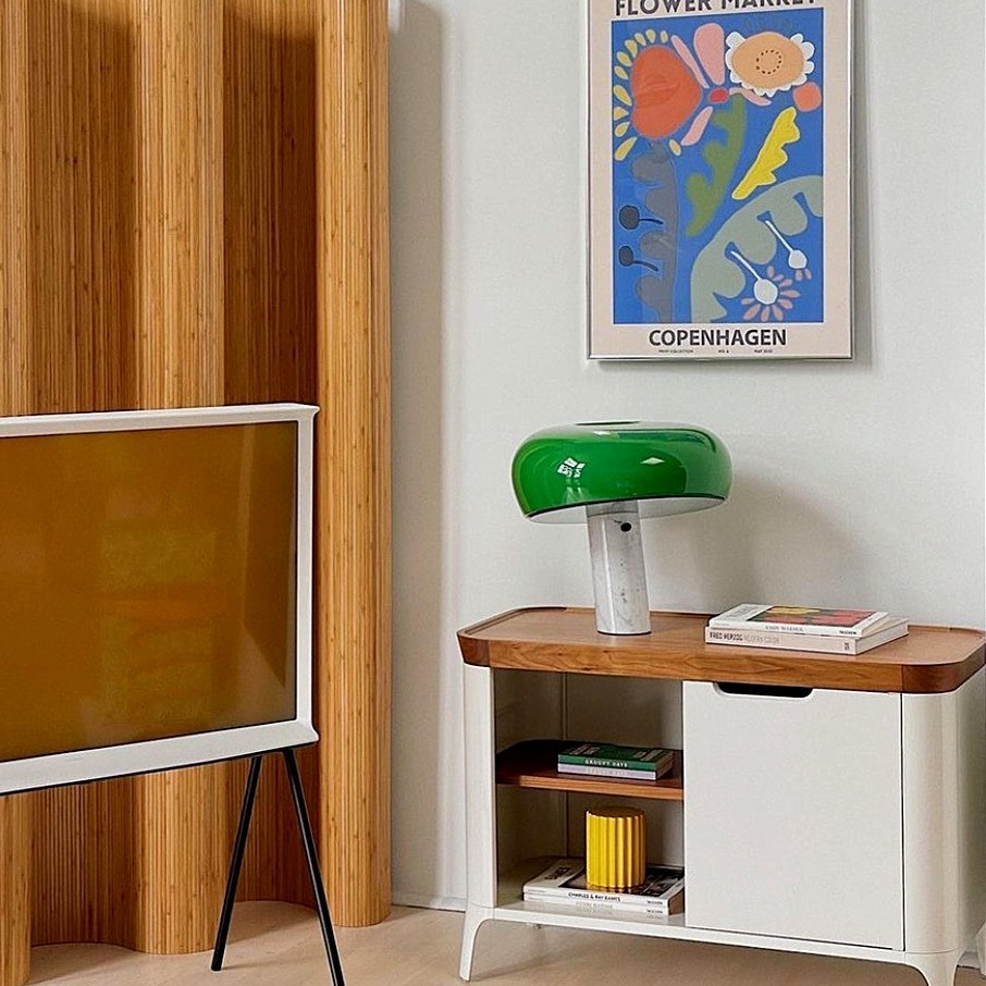 Lámpara de mesa curva de mármol verde sobre una pequeña mesa auxiliar en una sala de estar.
