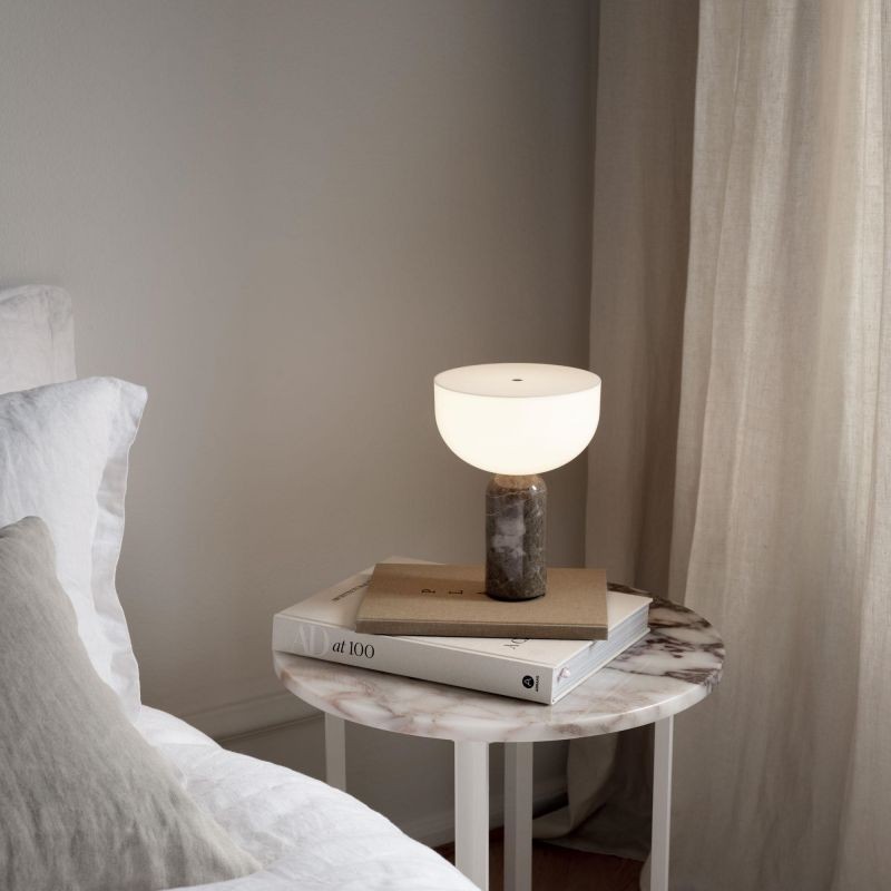 Lampa Kizu obok książek na stoliku nocnym
