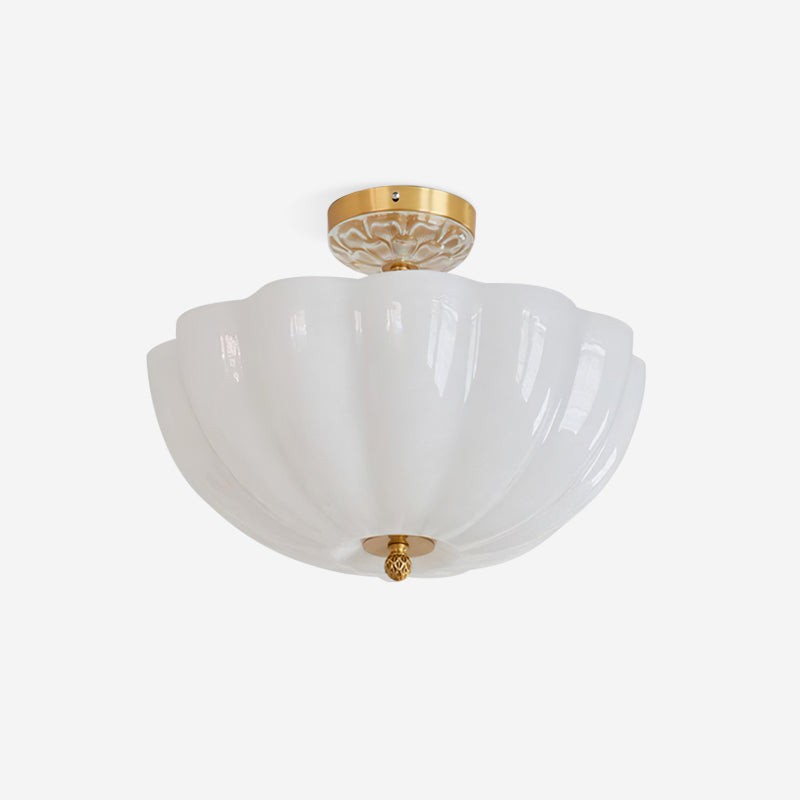 Isolert utsikt over taklampen med blomstermotiv i messing og melkehvitt glass