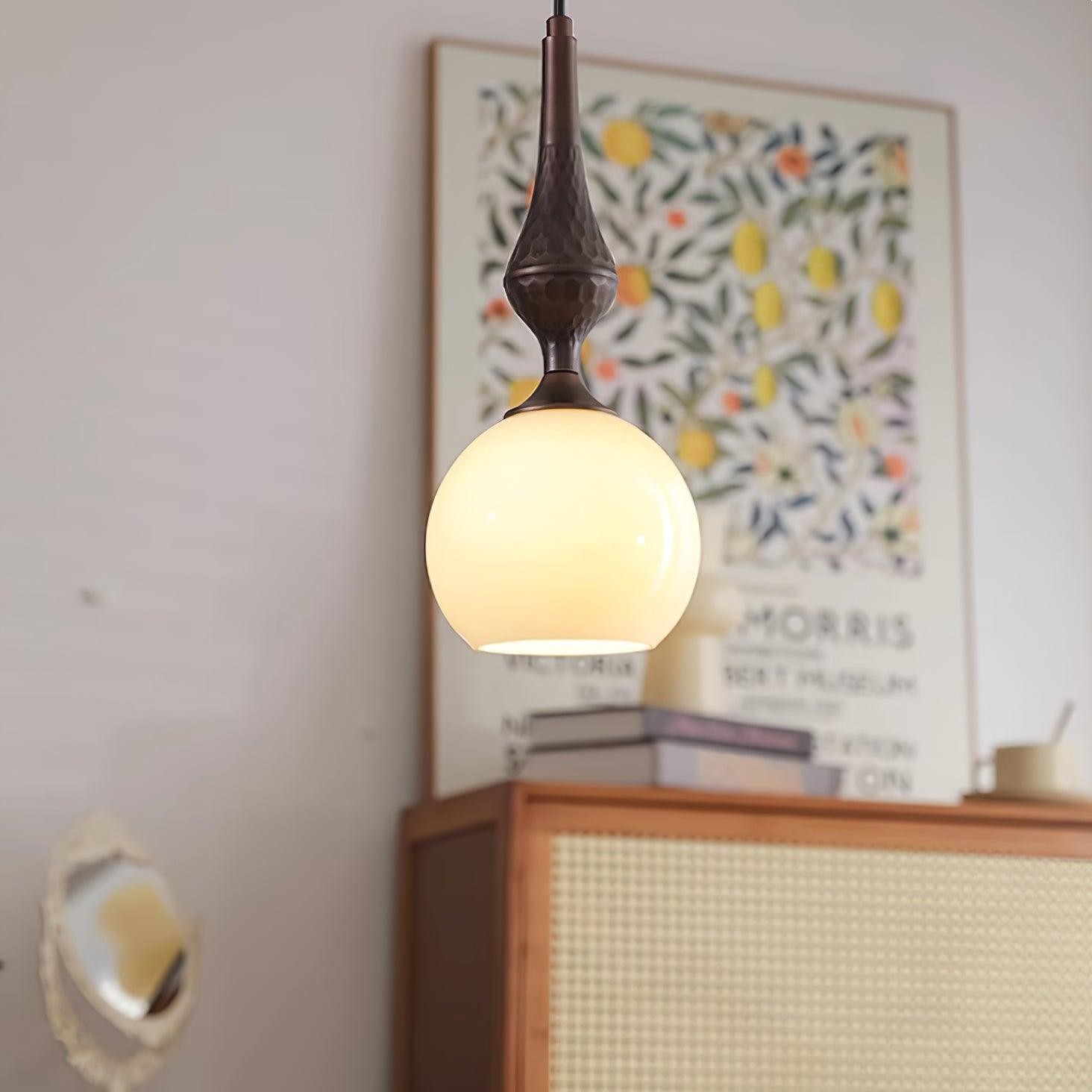 Lampa wisząca Globe oświetlona w stylowym pokoju z oprawionymi dziełami sztuki