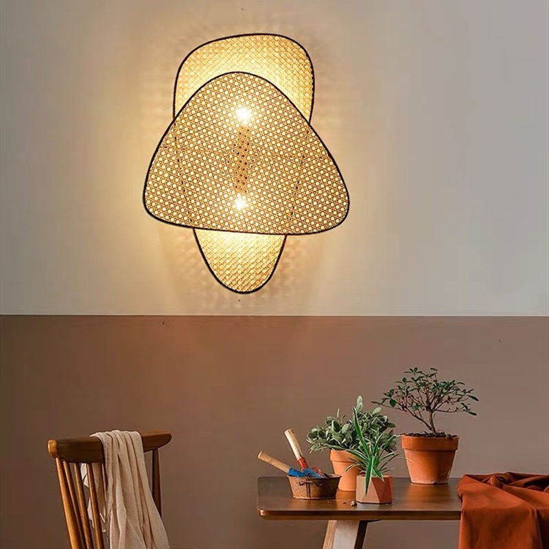 Rattan-Wandleuchte über Tisch und Pflanzen