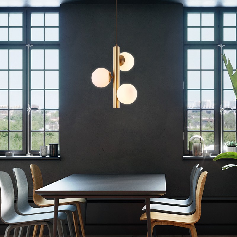 Pendellampa med tre glaskulor ovanför ett matbord