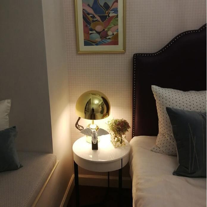 Lámpara de mesa Gold Bell sobre una mesita de noche.