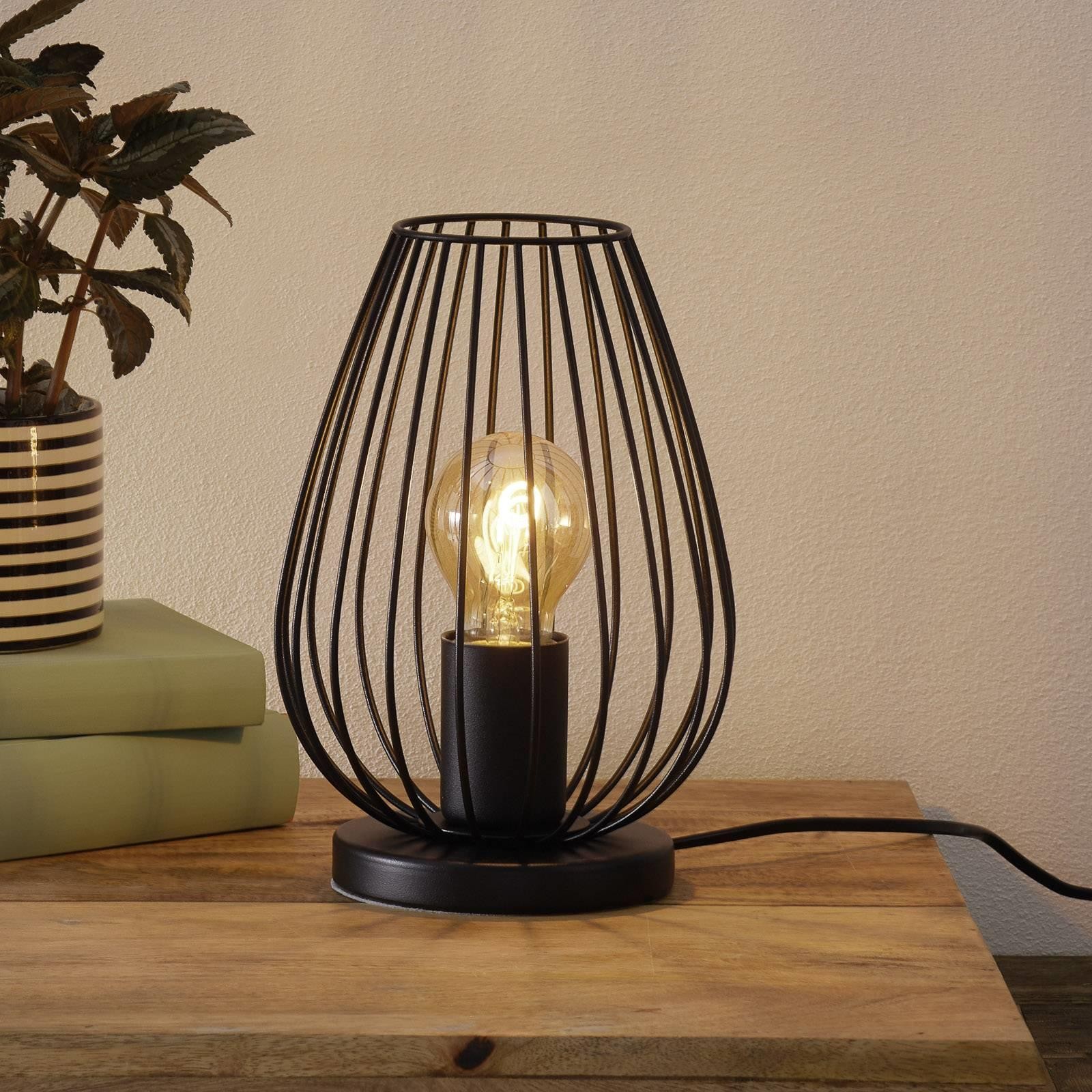 Lámpara de mesa S69 iluminada con una planta y un sofá de fondo.