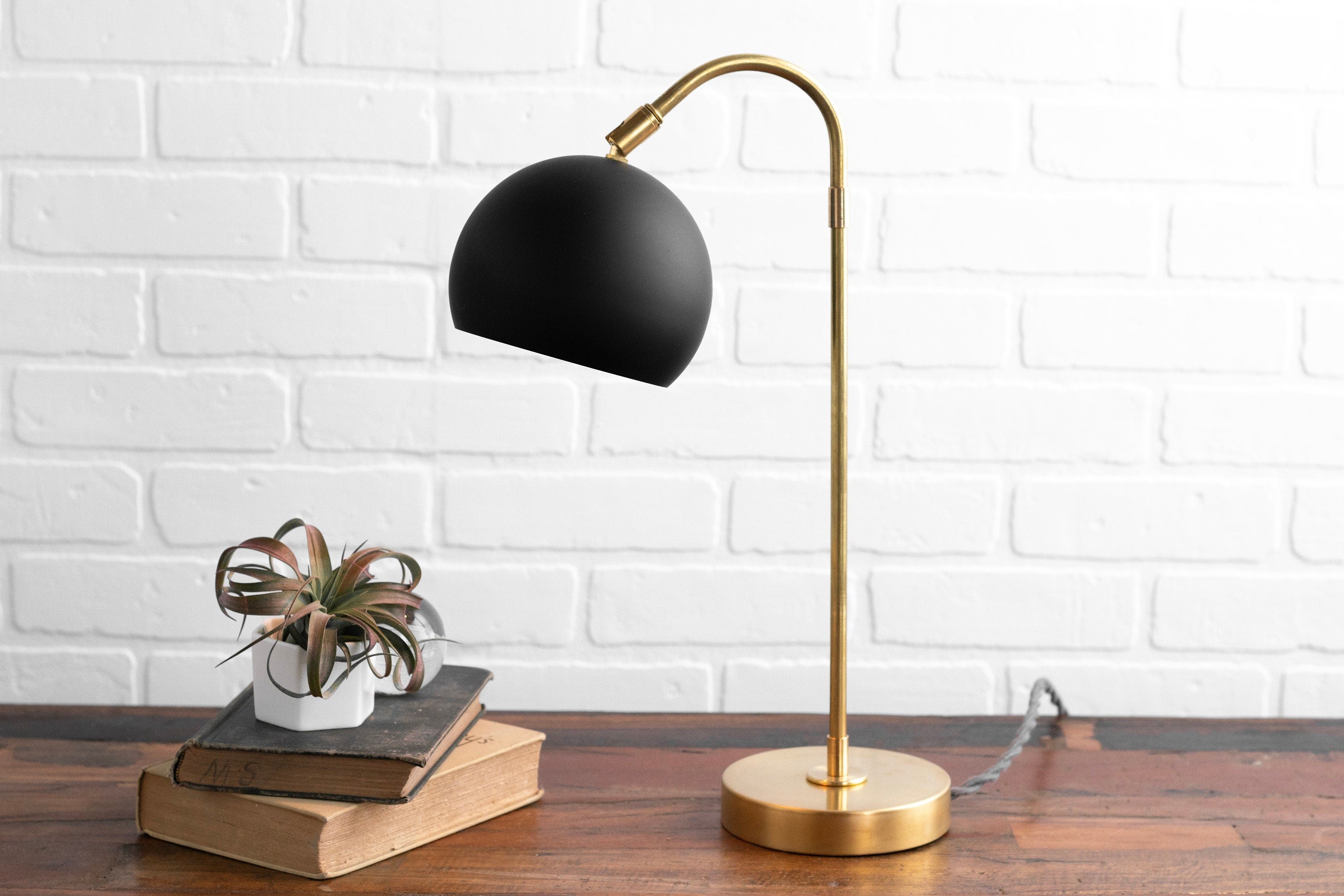 Lampa na złotej podstawie Ornato Luxe z książkami i rośliną