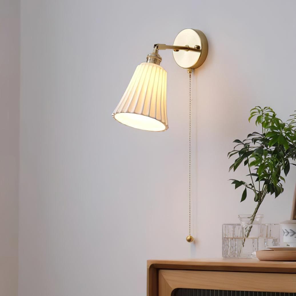 Zapalona lampa ścienna nad meblami i dekoracjami roślinnymi