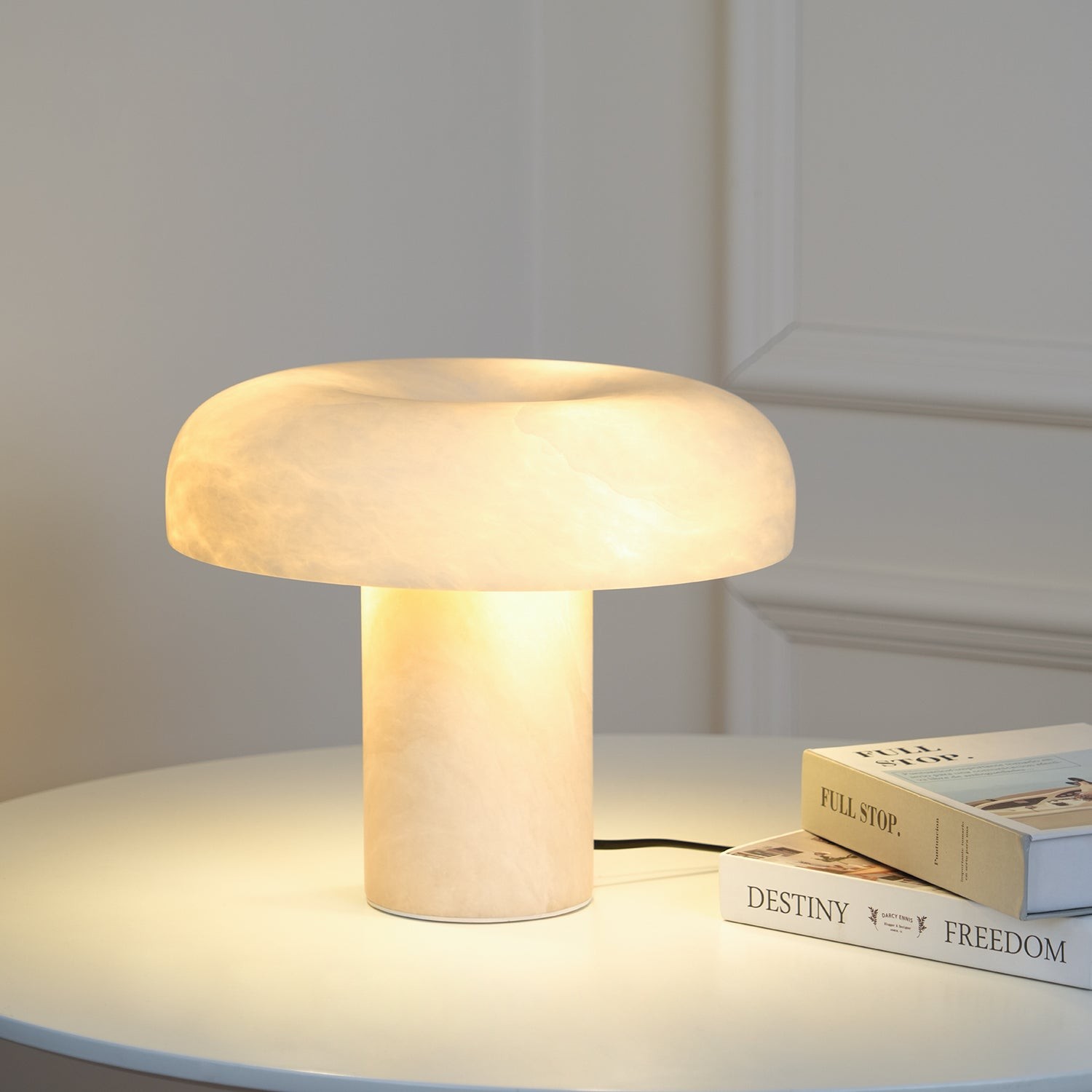 Zapalona alabastrowa lampa M450 na blacie z książkami