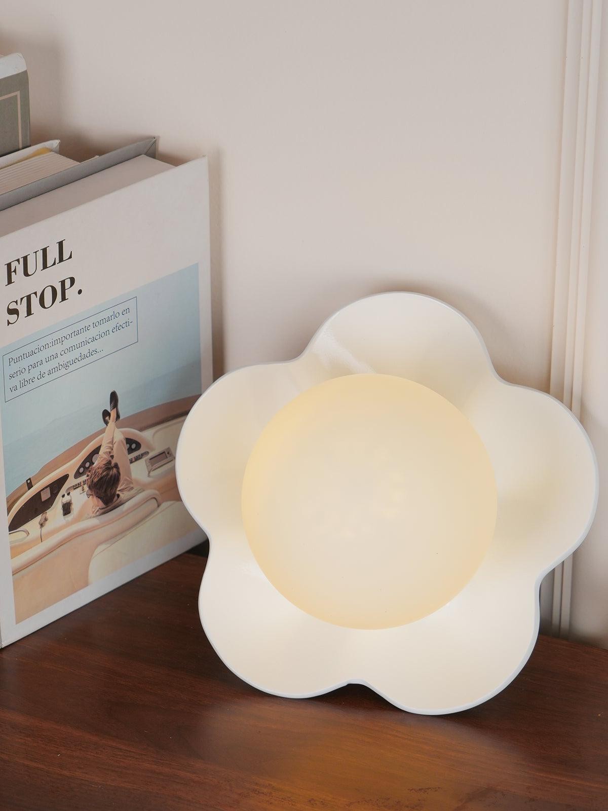 Biała lampa La Fleur na blacie obok książek