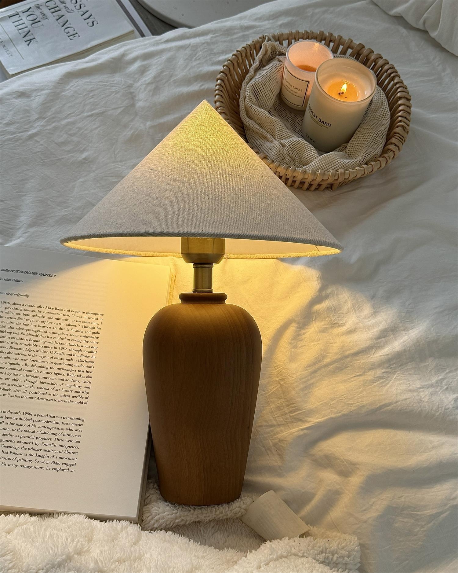 Lampa Brayden zapalona w sypialni książką i świecami