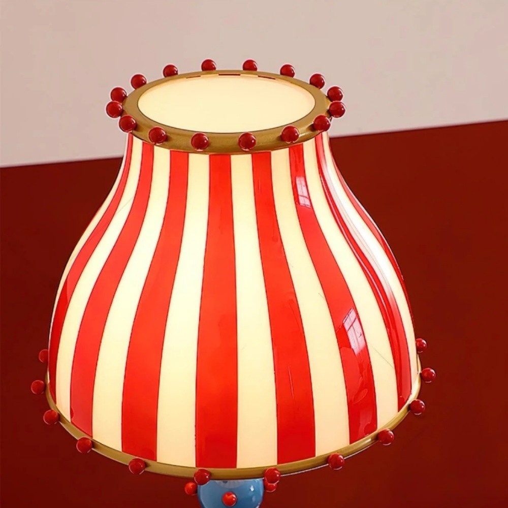Primer plano de la pantalla de cristal a rayas iluminada y los detalles de las cuentas en la lámpara de pie Festilo Circus.