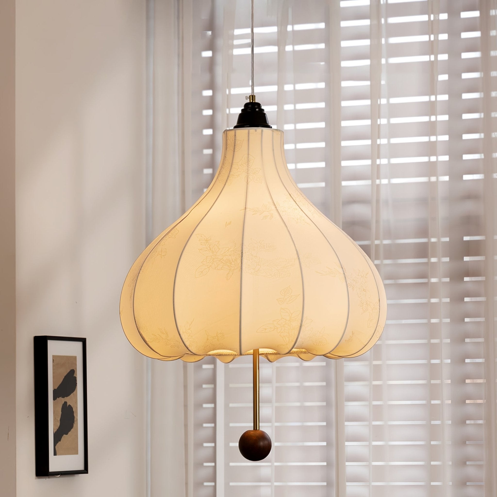 Lampa wisząca z kasztanowej tkaniny, umieszczona centralnie w pobliżu żaluzji okiennych